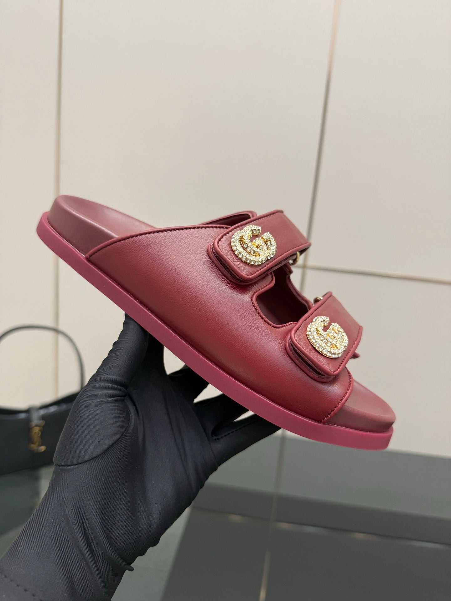 Red Gucci slide sandal, side view, with two straps and gold-tone logo buckles