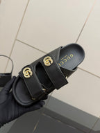 Gucci ladies black slide sandal closeup with embossed GUCCI on footbed