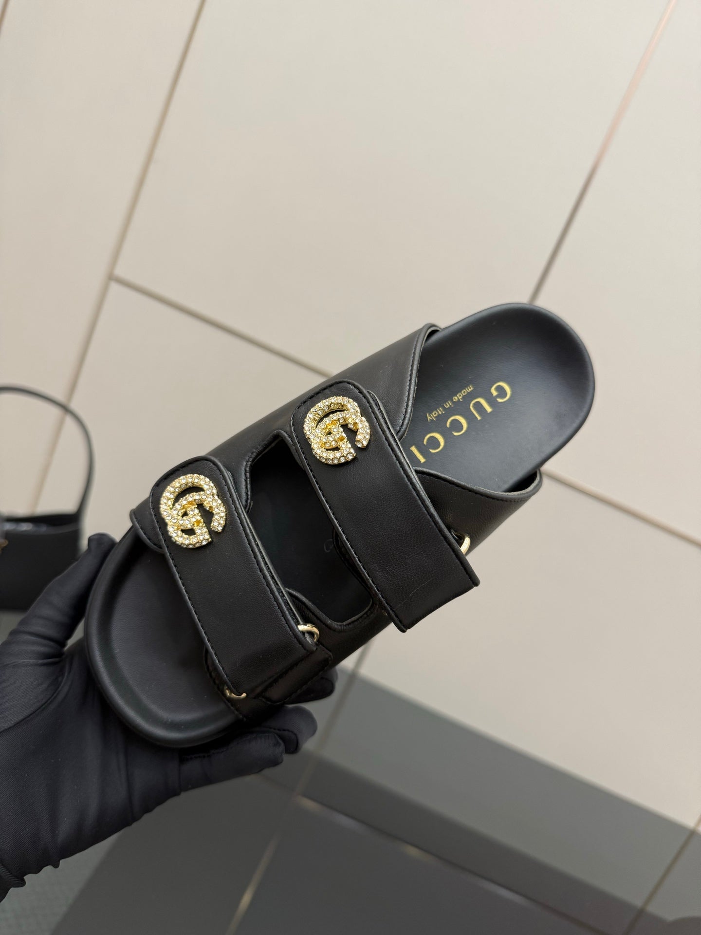 Gucci ladies black slide sandal closeup with embossed GUCCI on footbed