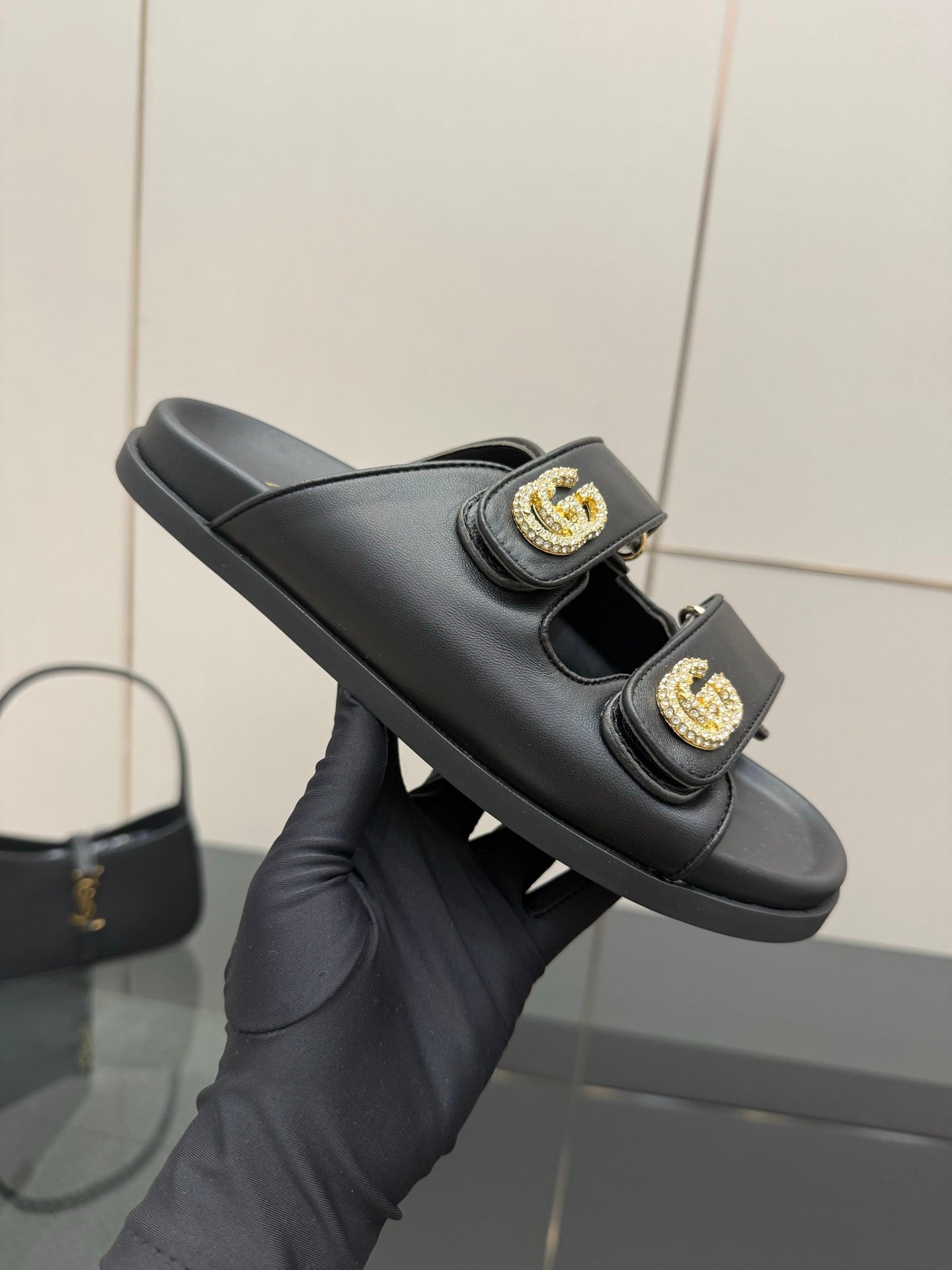 Gucci ladies black slide sandal, close view of gold G buckle straps