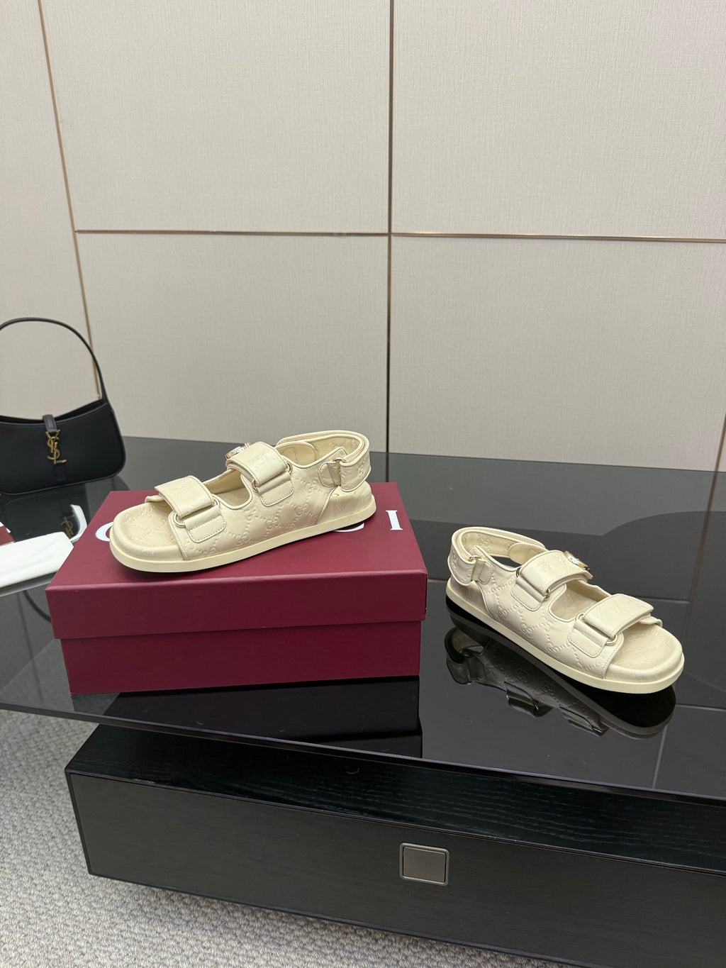 Cream slide sandals pair view; metal buckle straps on textured leather