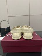 Cream slide sandals with embossed pattern on straps and footbed