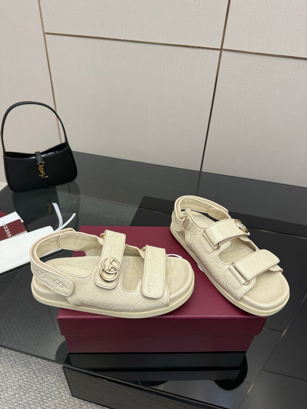 Cream slide sandals with chunky strap, buckle closure, and embossed logo finish