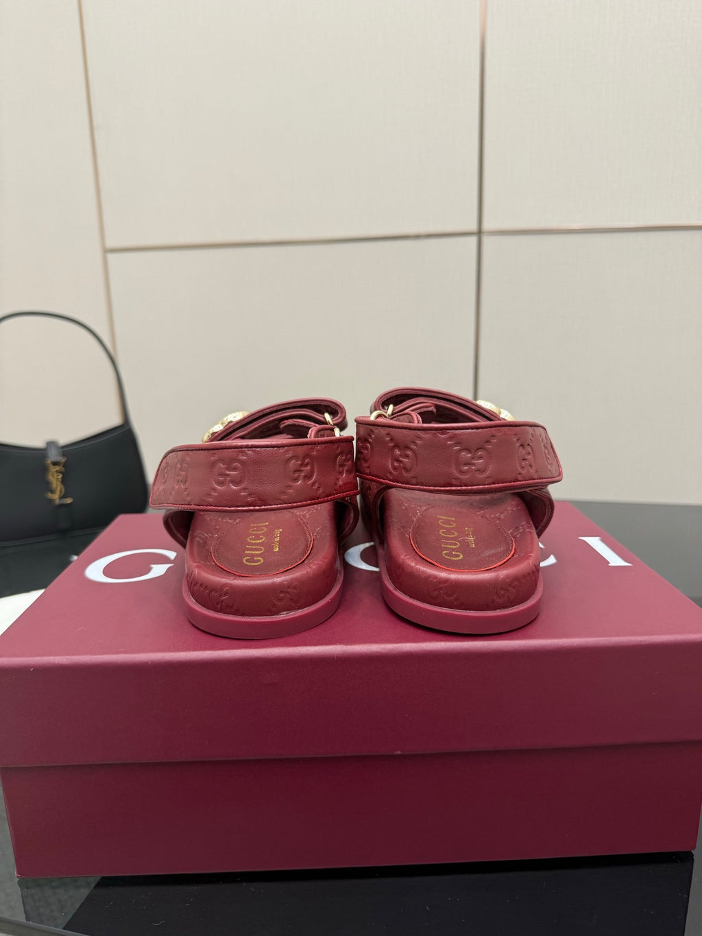 Red Gucci logo-buckle sandals, heel and back strap view, on pink box