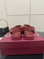 Red Gucci logo-buckle sandals, heel and back strap view, on pink box