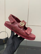 Red Gucci logo-buckle slide sandal held in black glove, top view
