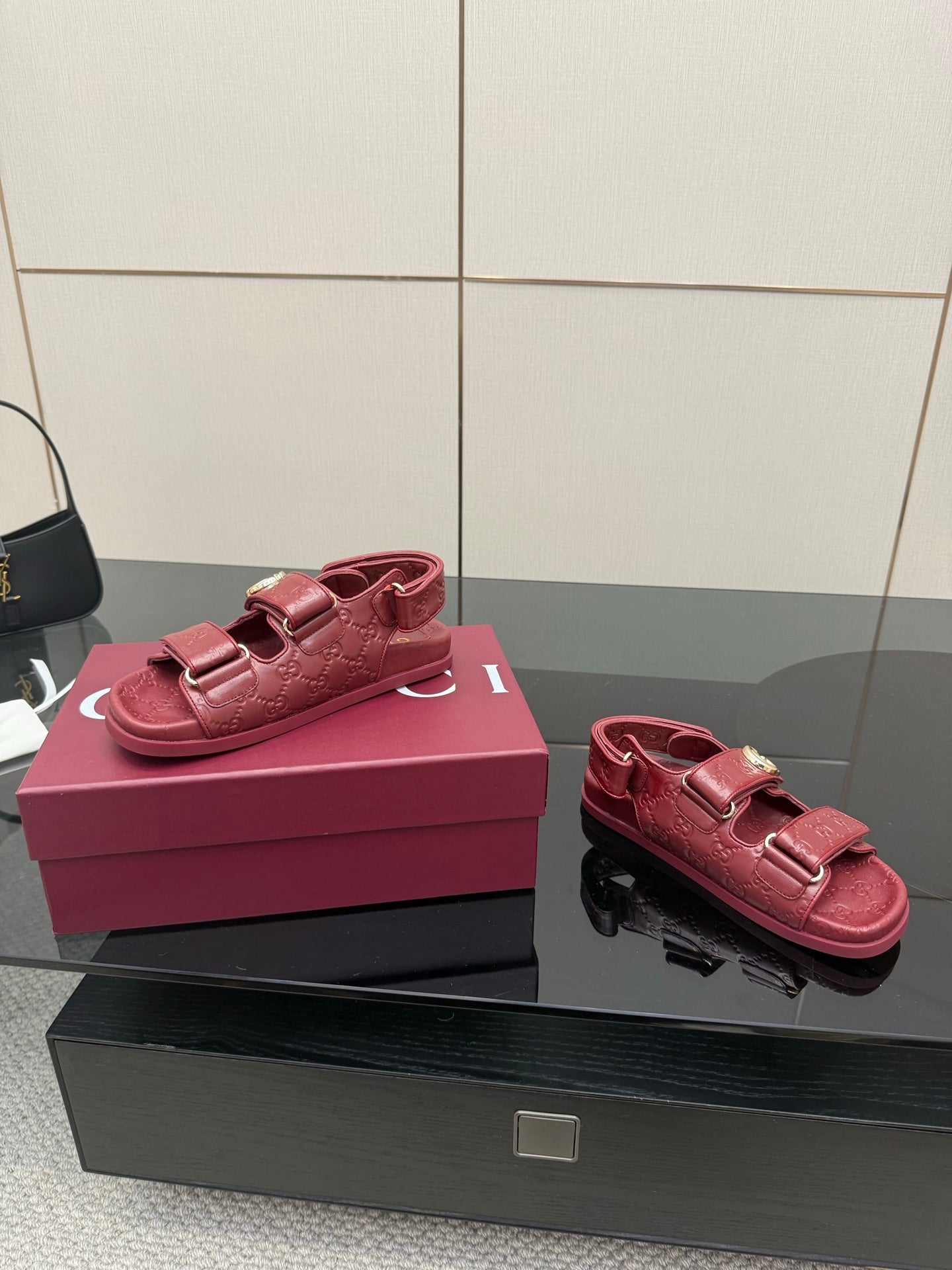 Red Gucci logo-buckle sandals, side view with thick sole, on pink box