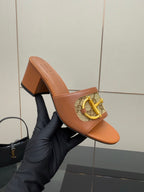 Women's Gucci tan mule sandal on hand, showing patterned front strap and block heel