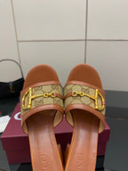 Close-up of women's Gucci tan slide sandals with gold horsebit on logo-patterned strap
