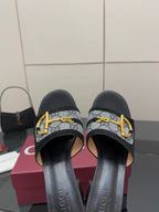 Black slides with GG-print straps and gold buckle, close-up front view