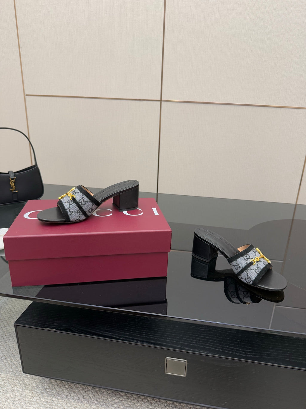 Black block-heel slides with GG-print strap and gold buckle, angled side view