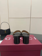 Black slide sandals with GG-print straps and gold hardware, back view on box
