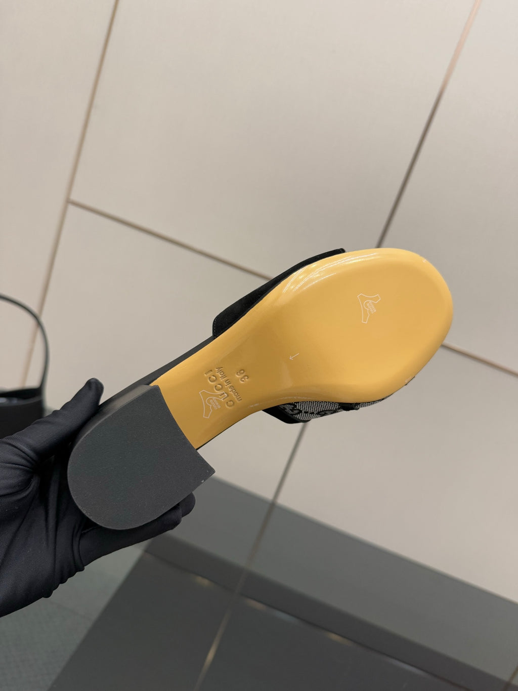 Yellow sole of black slide sandal with embossed logo, underside view