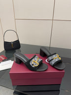 Black slide sandals with GG-print straps, gold buckle detail, block heel pair