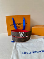 Louis Vuitton monogram belt with red underside and silver LV buckle on dust bag