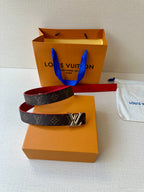Louis Vuitton monogram belt with red interior and silver LV buckle on dust bag