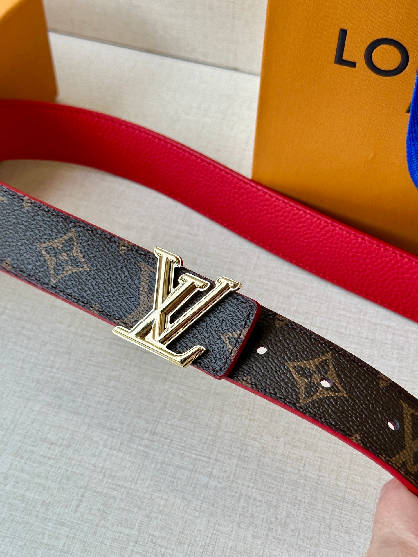 Louis Vuitton monogram belt with red lining and silver LV buckle close-up