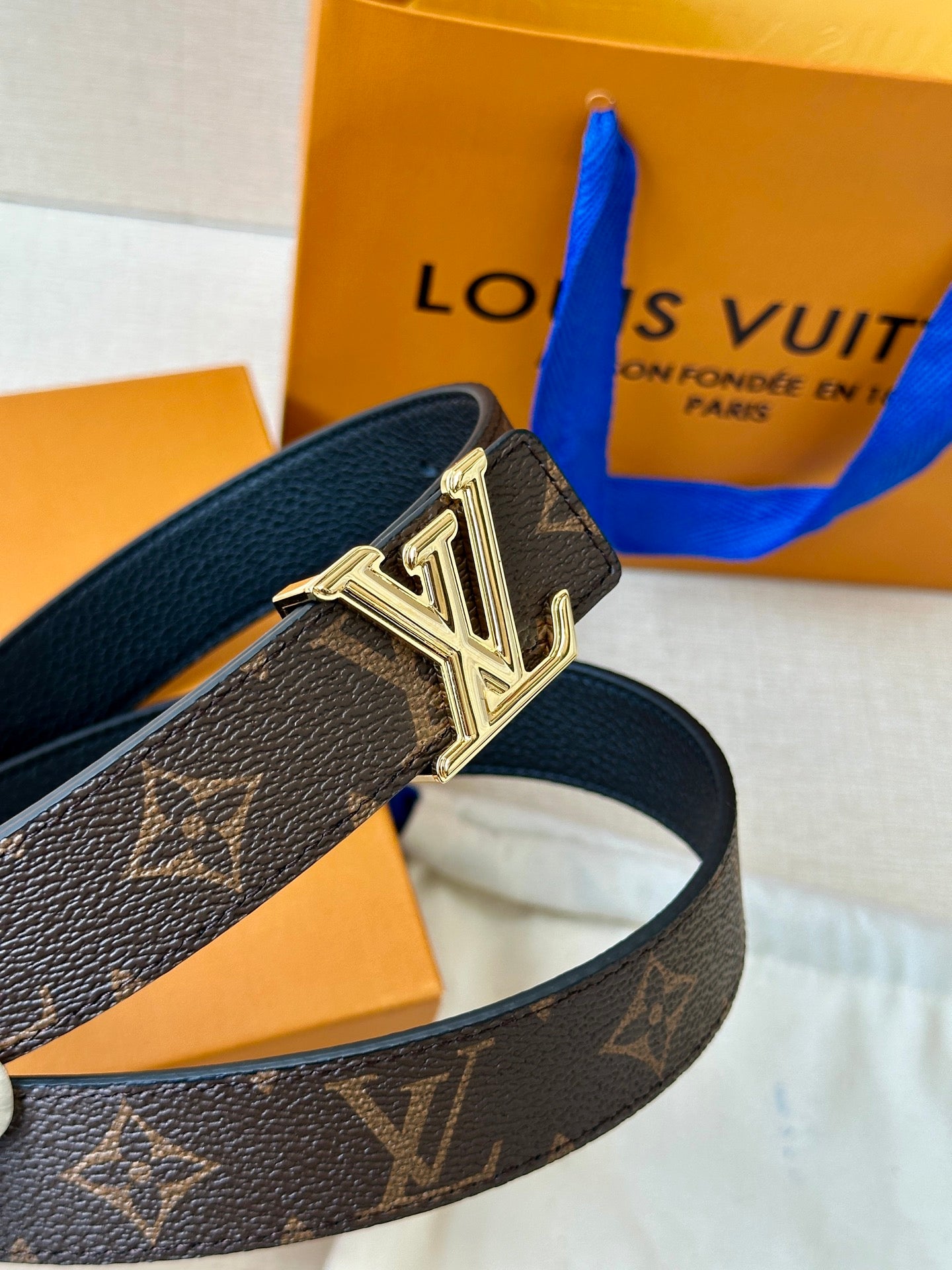 Gold-tone LV buckle on brown monogram belt strap with textured leather