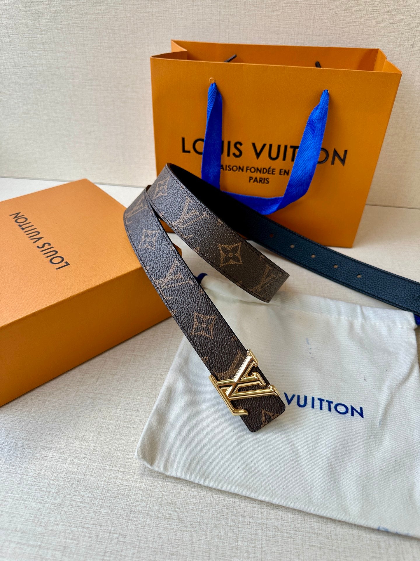 Monogram belt and gold-tone LV buckle resting on a fabric pouch