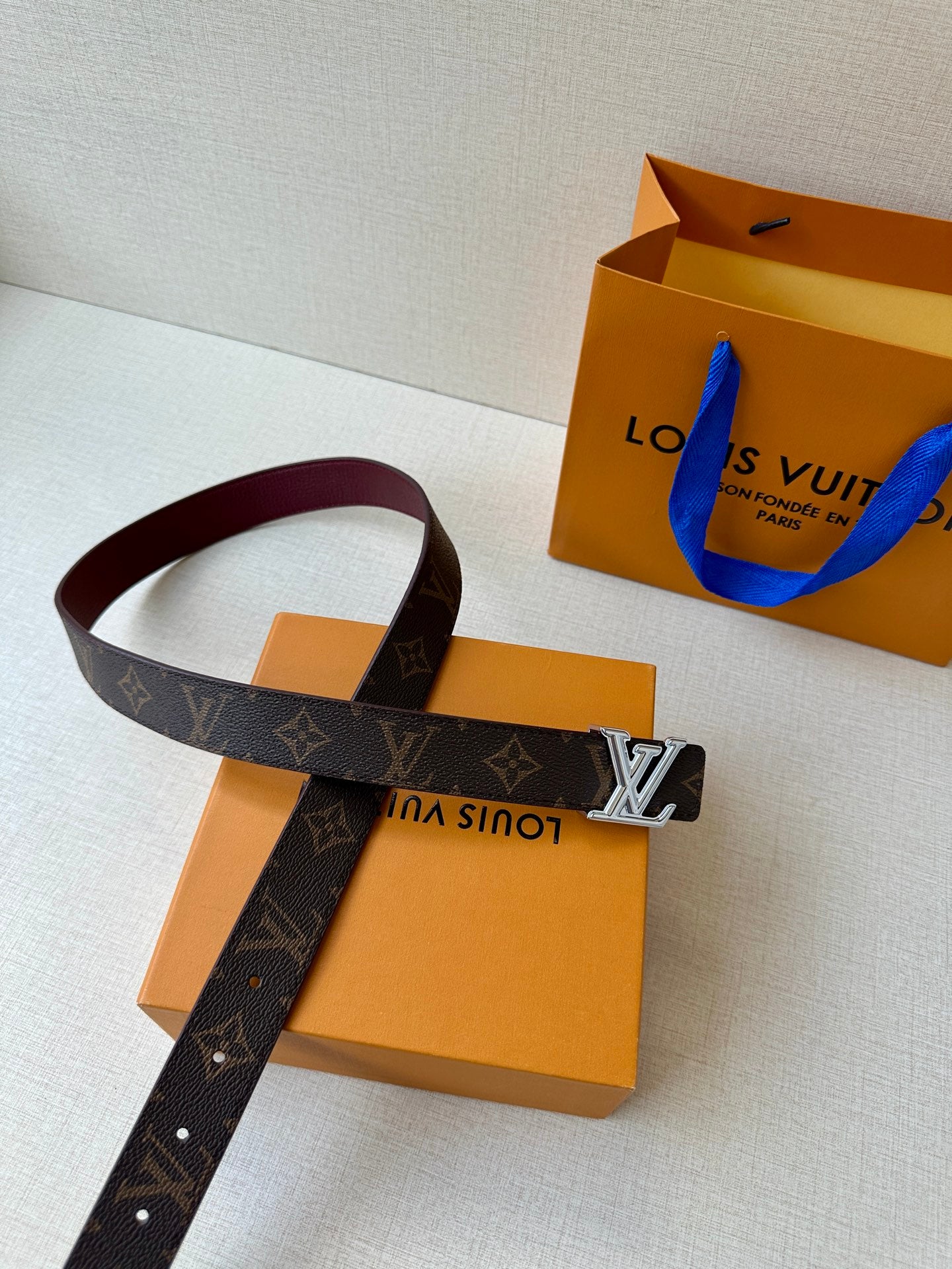 Louis Vuitton monogram belt with silver-tone buckle on burgundy-lined strap