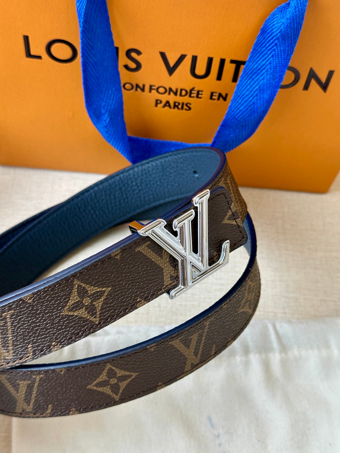Monogram belt close-up with gold LV buckle on dark leather strap