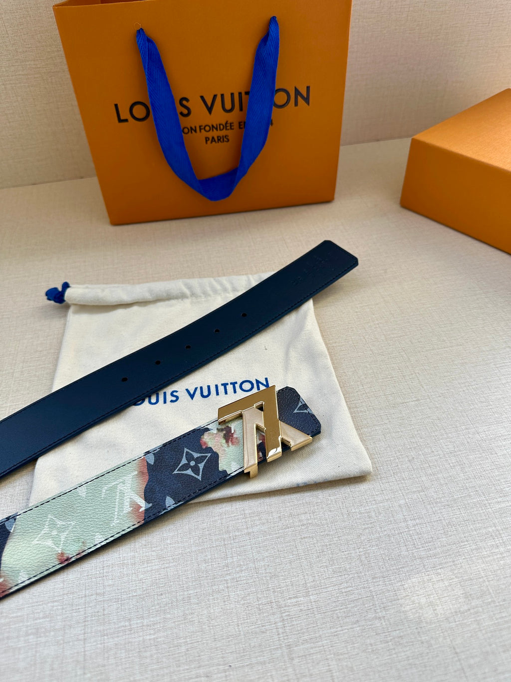 Monogram leather belt strap with gold-tone LV buckle and perforated holes.