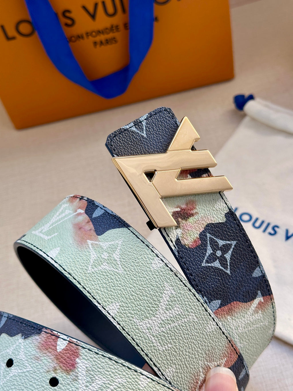 Two-tone monogram belt close-up with gold-tone LV buckle and textured leather.