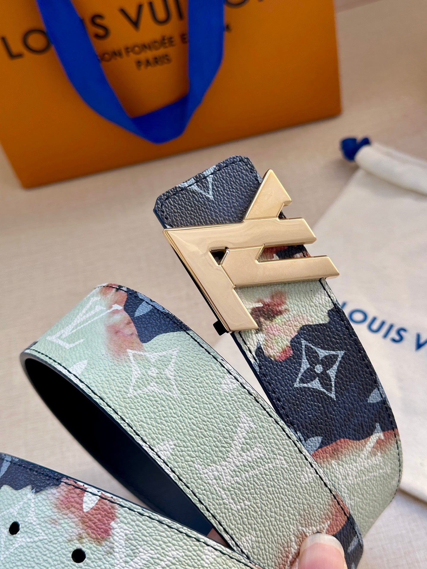 Two-tone monogram belt close-up with gold-tone LV buckle and textured leather.