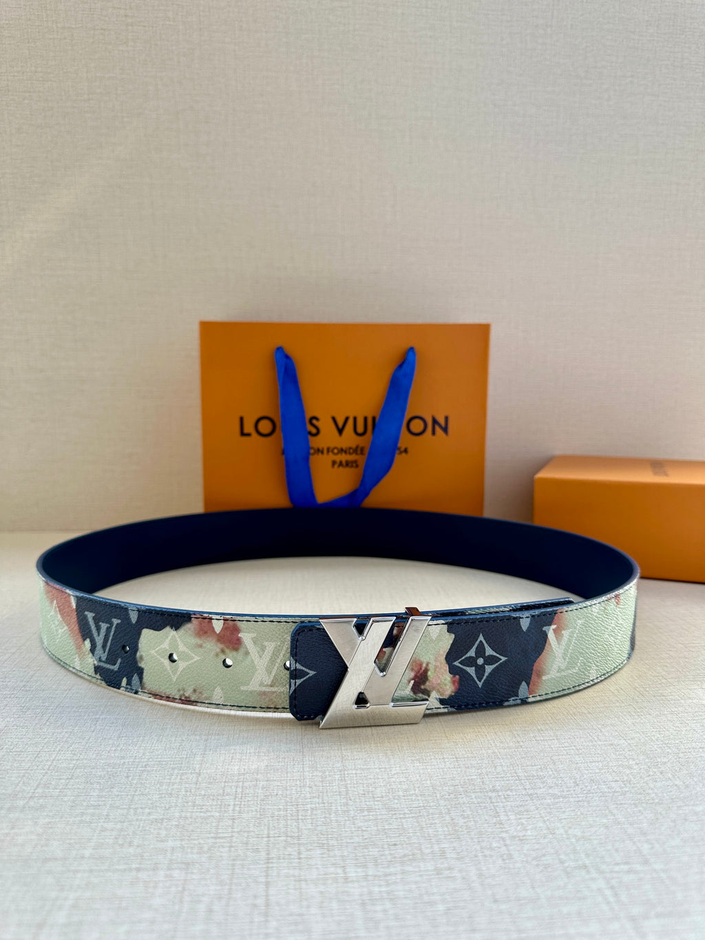Two-tone monogram leather belt with gold-tone LV buckle and floral pattern strap.