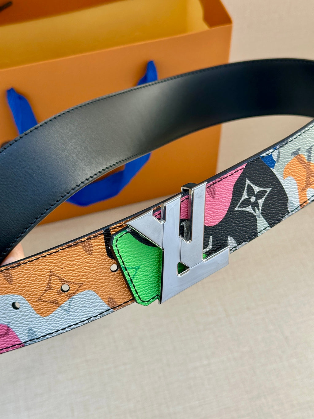 Multicolor Louis Vuitton belt detail: black strap with gold buckle and green accent