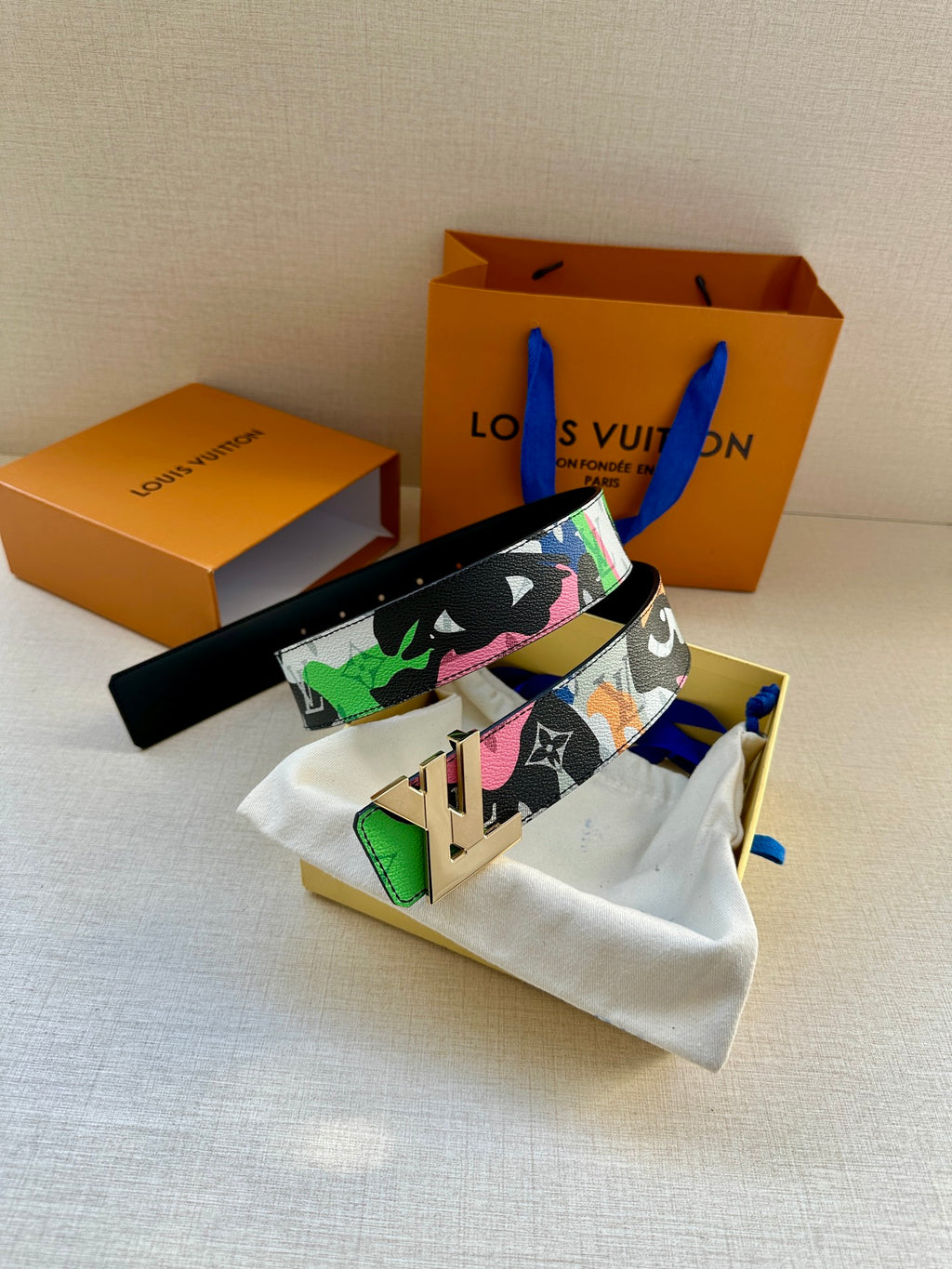 Multicolor designer belt with gold buckle, black strap, and matching pouch