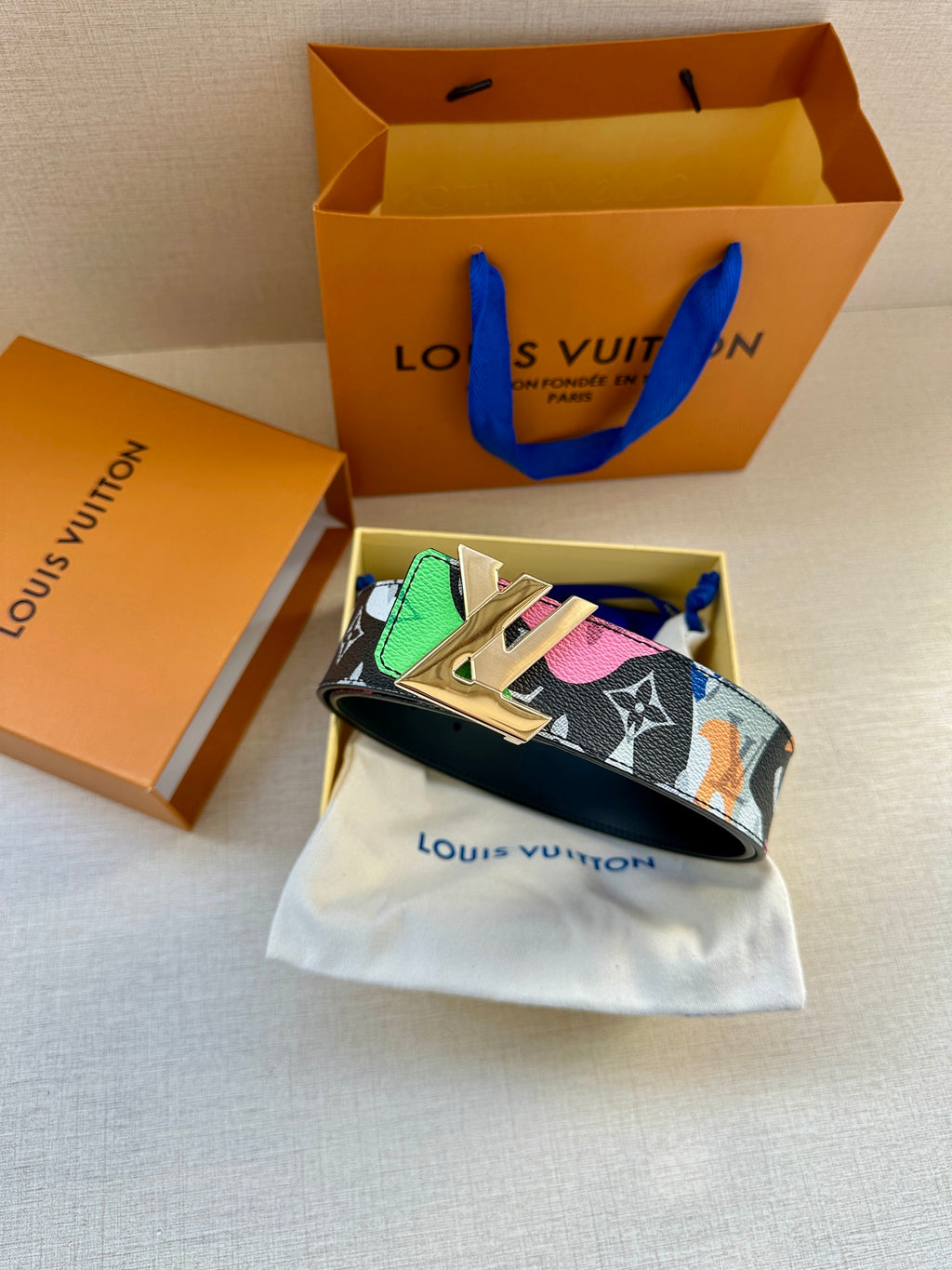 Designer belt on white pouch: multicolor strap with gold buckle and punch holes