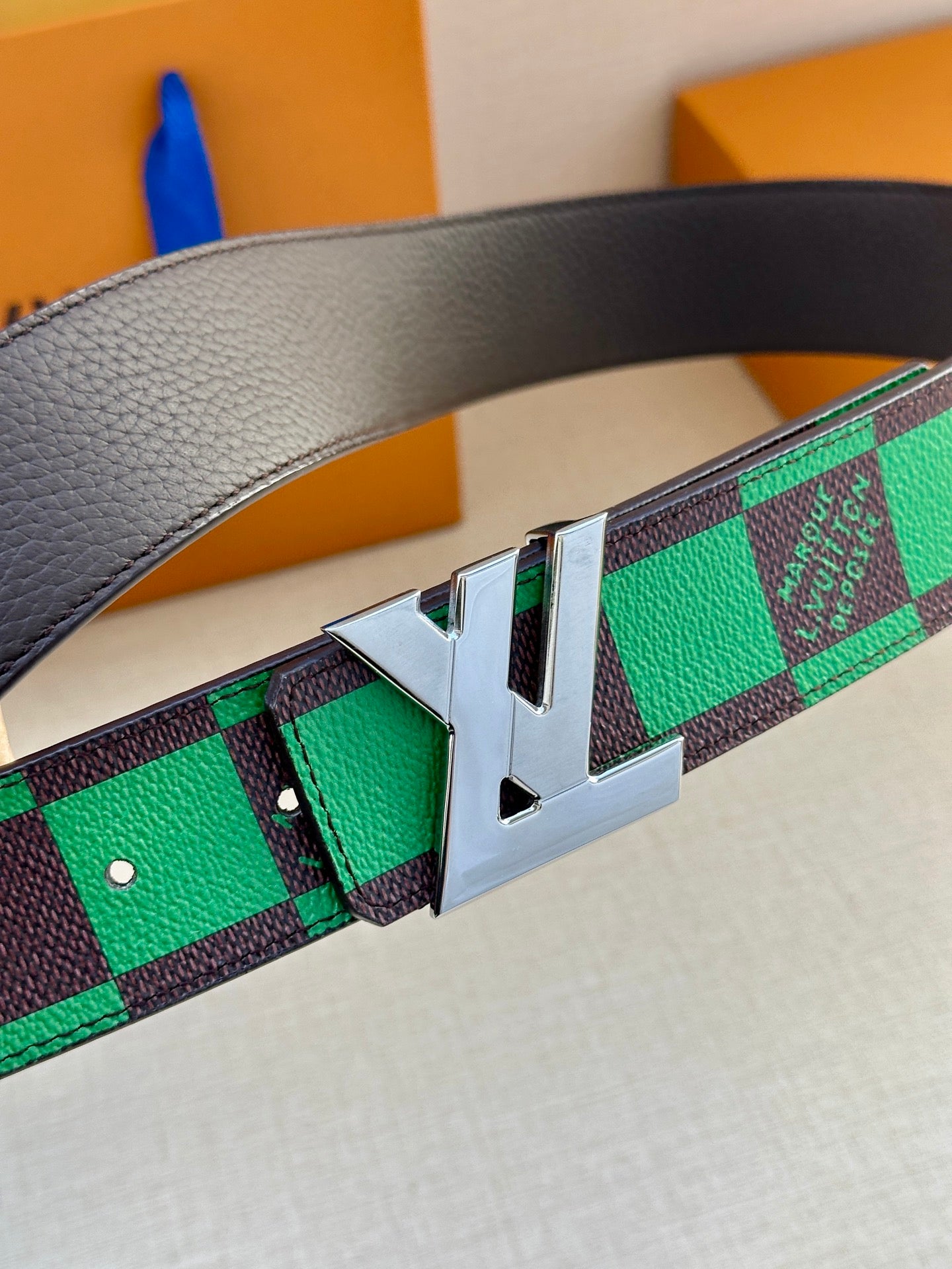 Louis Vuitton belt close-up: green check strap with silver pin buckle and studs