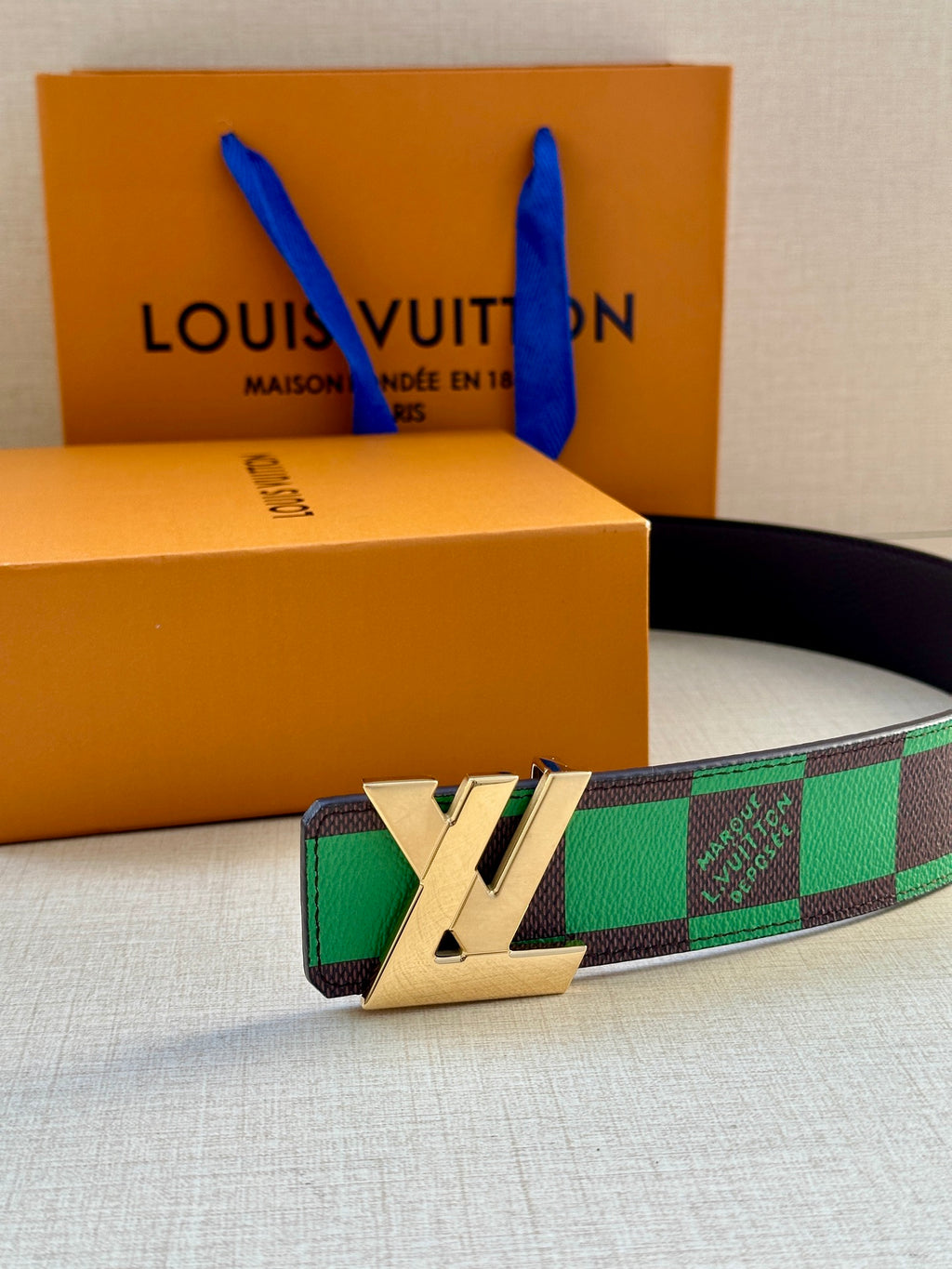Louis Vuitton belt with green check strap and gold-tone LV buckle on black leather