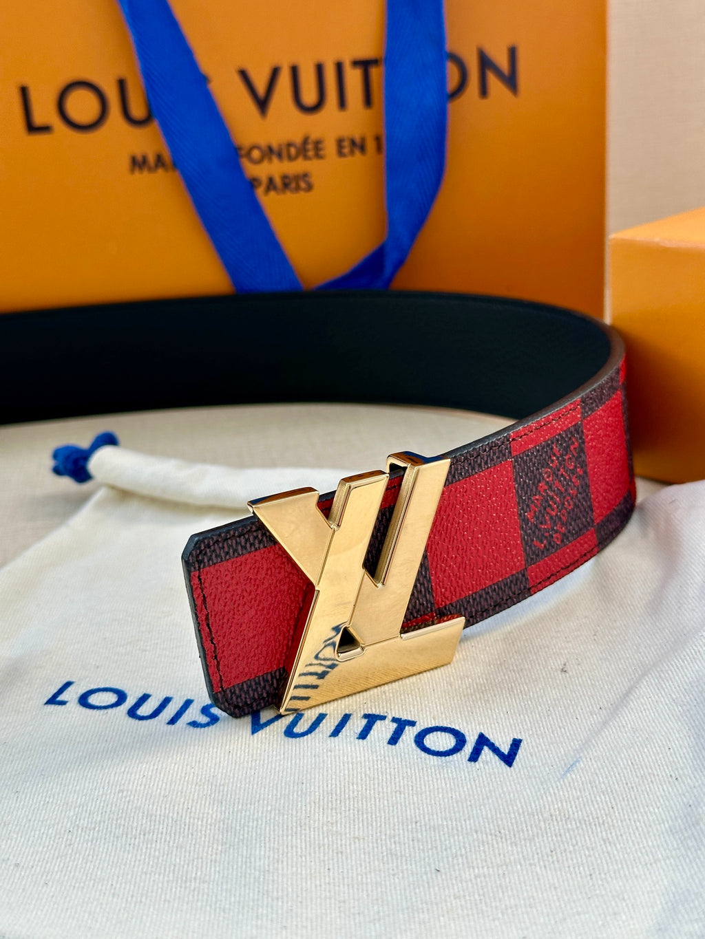 Louis Vuitton belt with check strap and gold LV logo buckle on white cloth