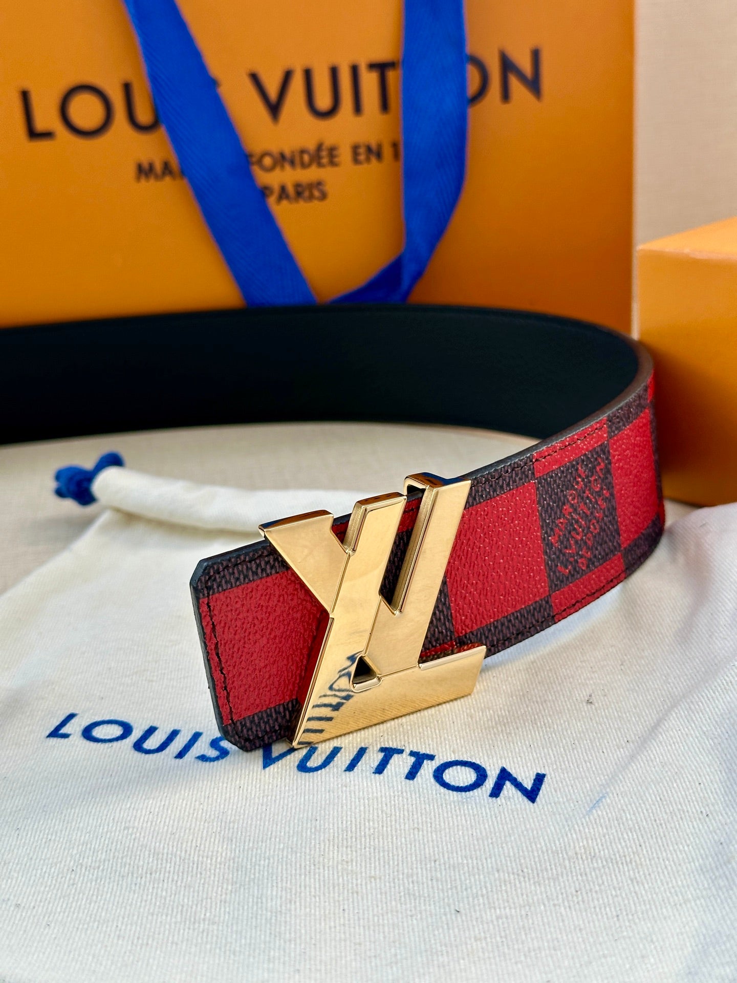 Louis Vuitton belt with check strap and gold LV logo buckle on white cloth