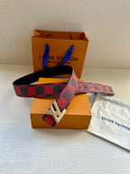 Louis Vuitton belt with checkered strap and gold buckle, across retail packaging