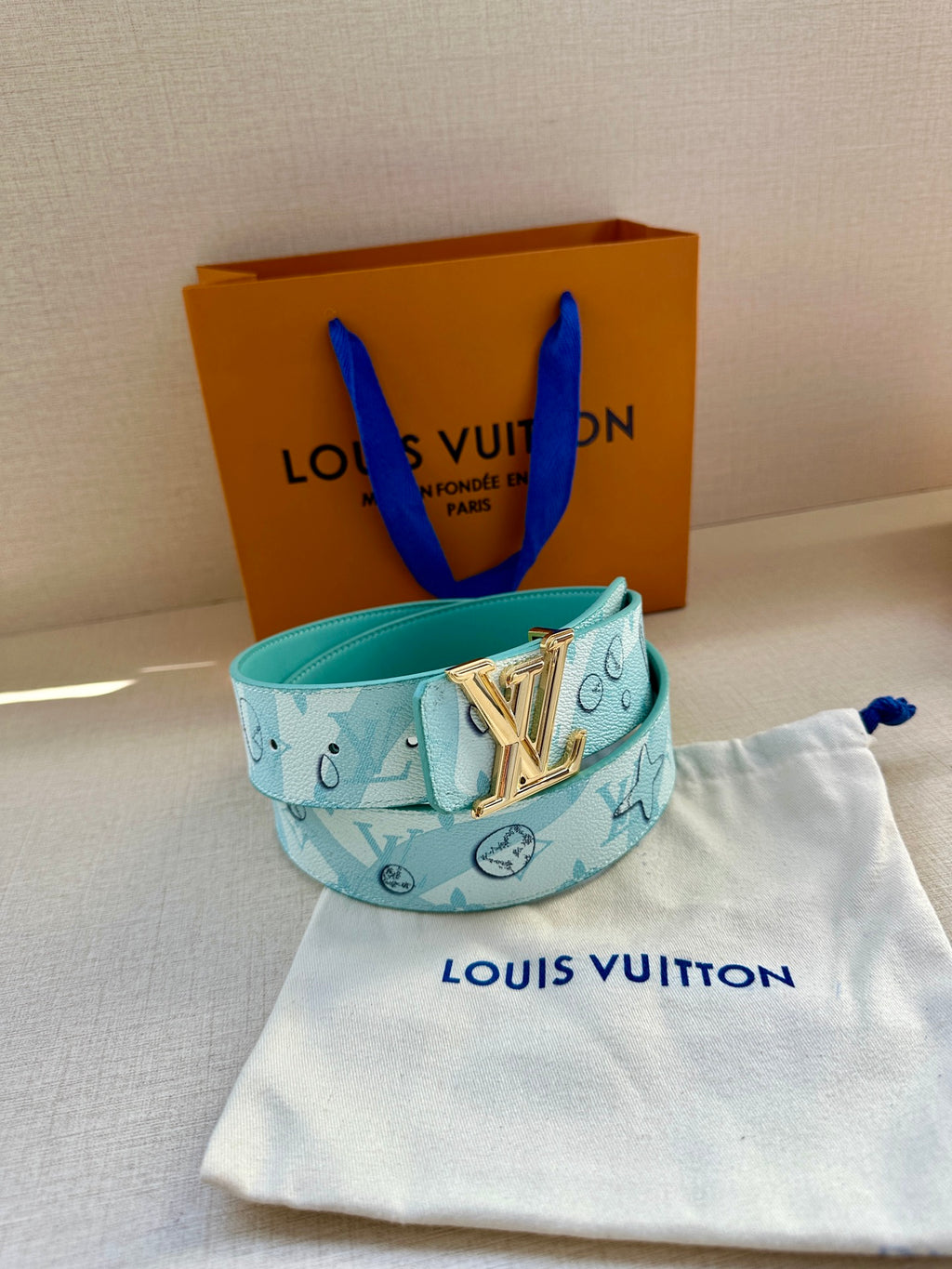 Turquoise Louis Vuitton belt with gold-tone LV buckle on fabric pouch