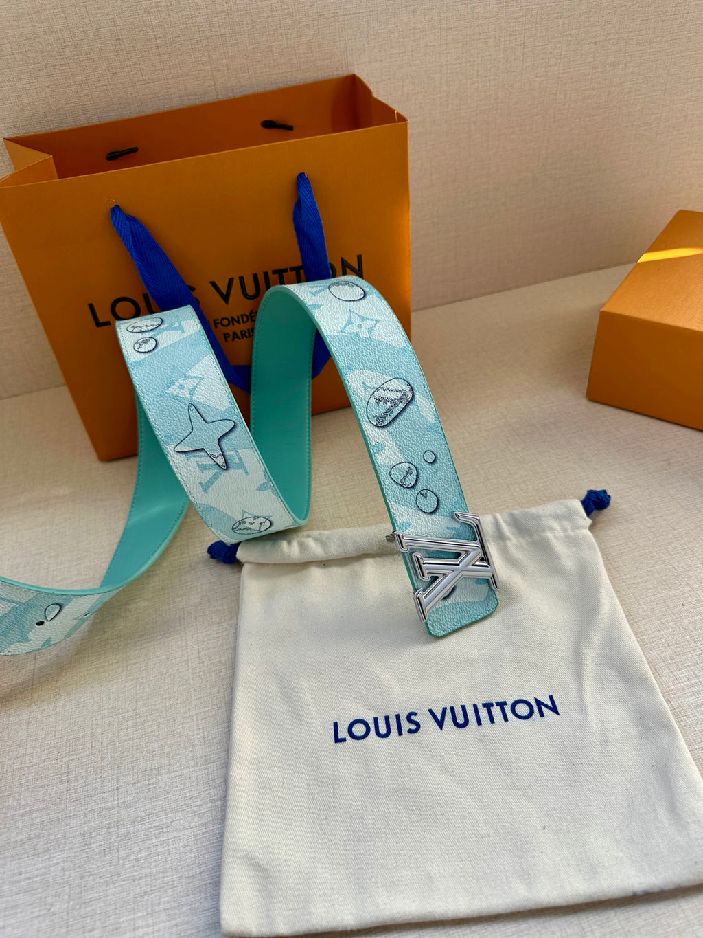 Turquoise belt strap with gold-tone LV buckle and logo pattern, shown with pouch