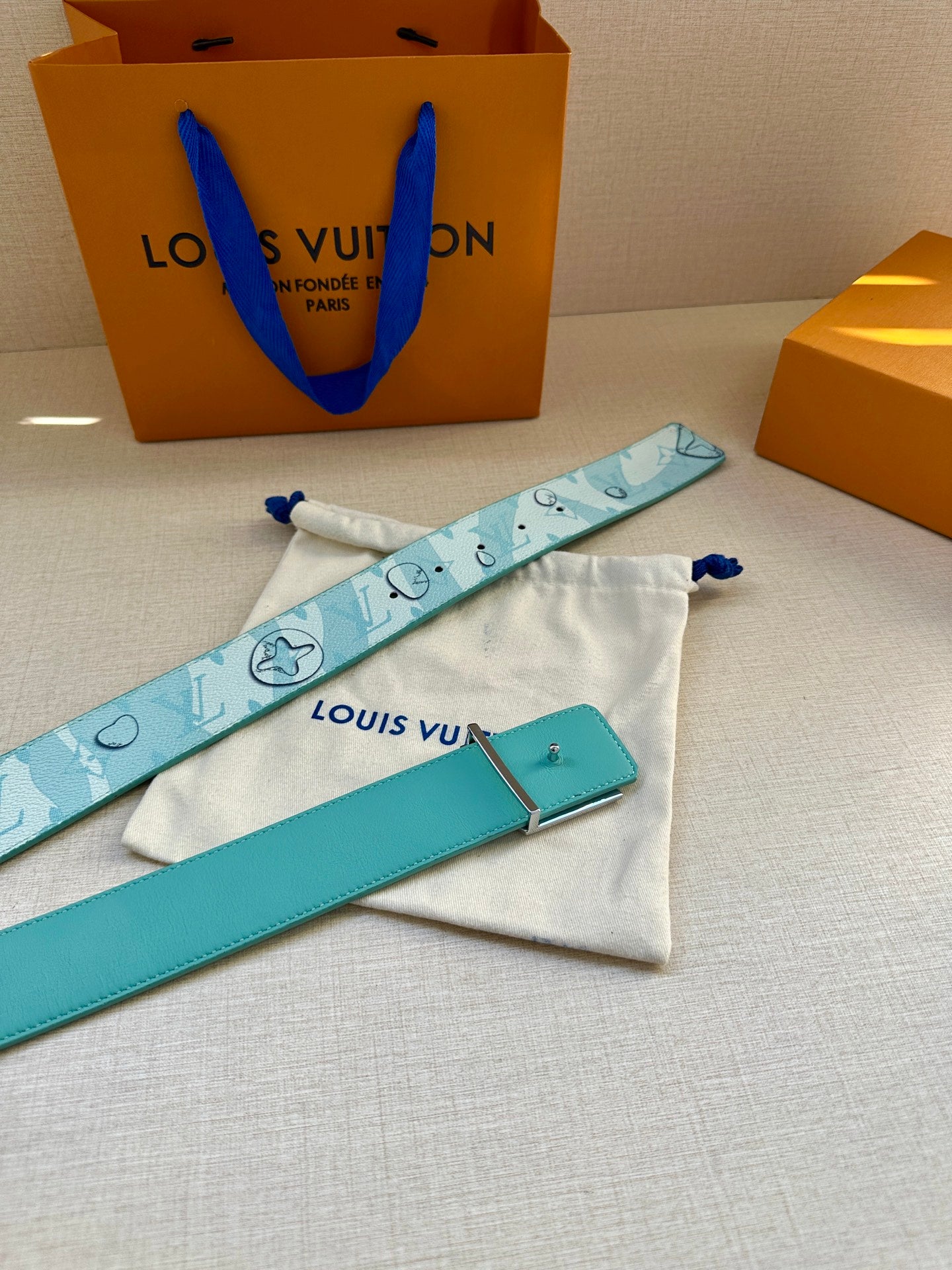 Turquoise logo belt with gold-tone LV buckle and matching pouch, laid flat