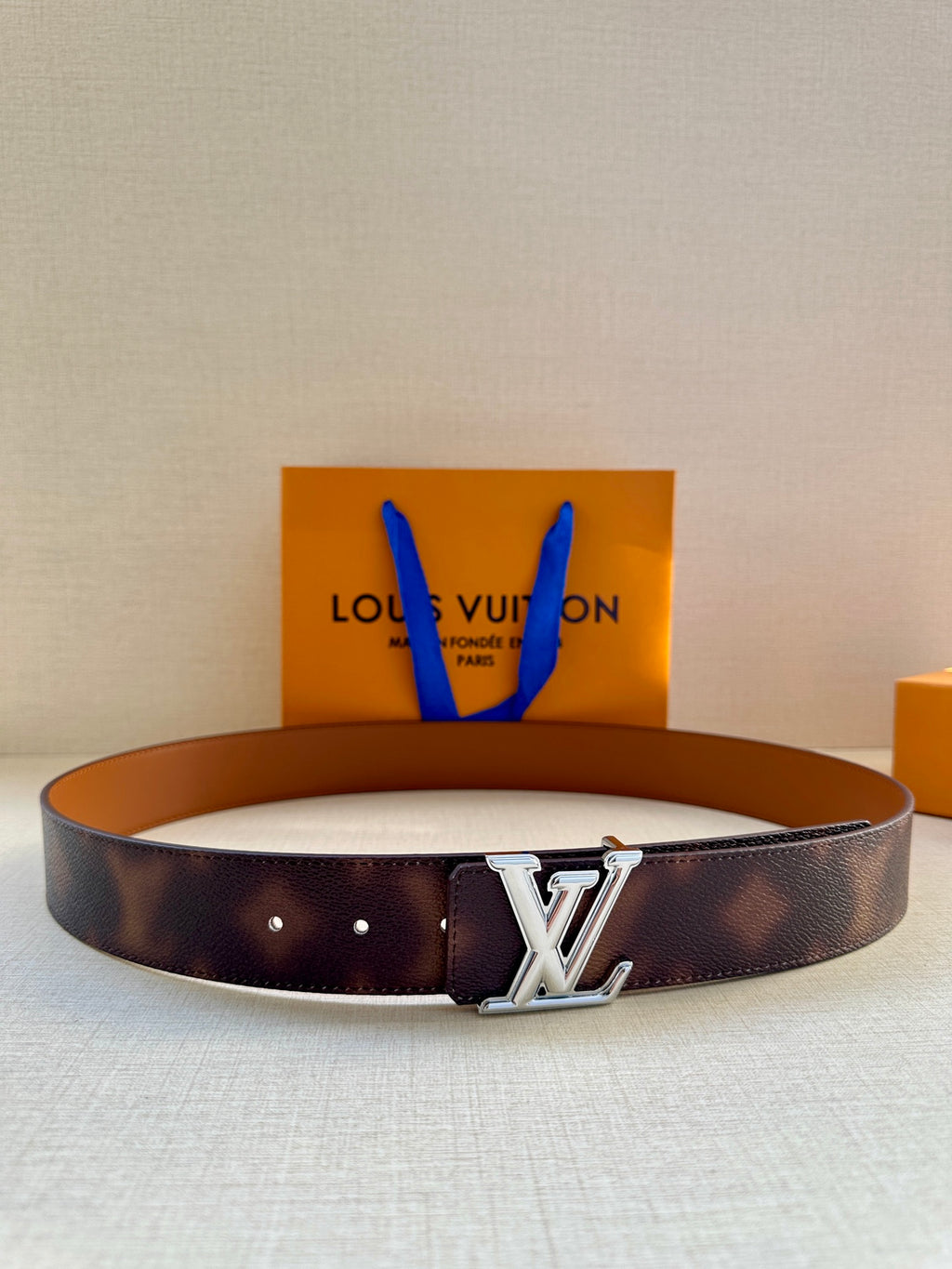 Louis Vuitton belt in dark brown leather with silver-tone LV buckle.