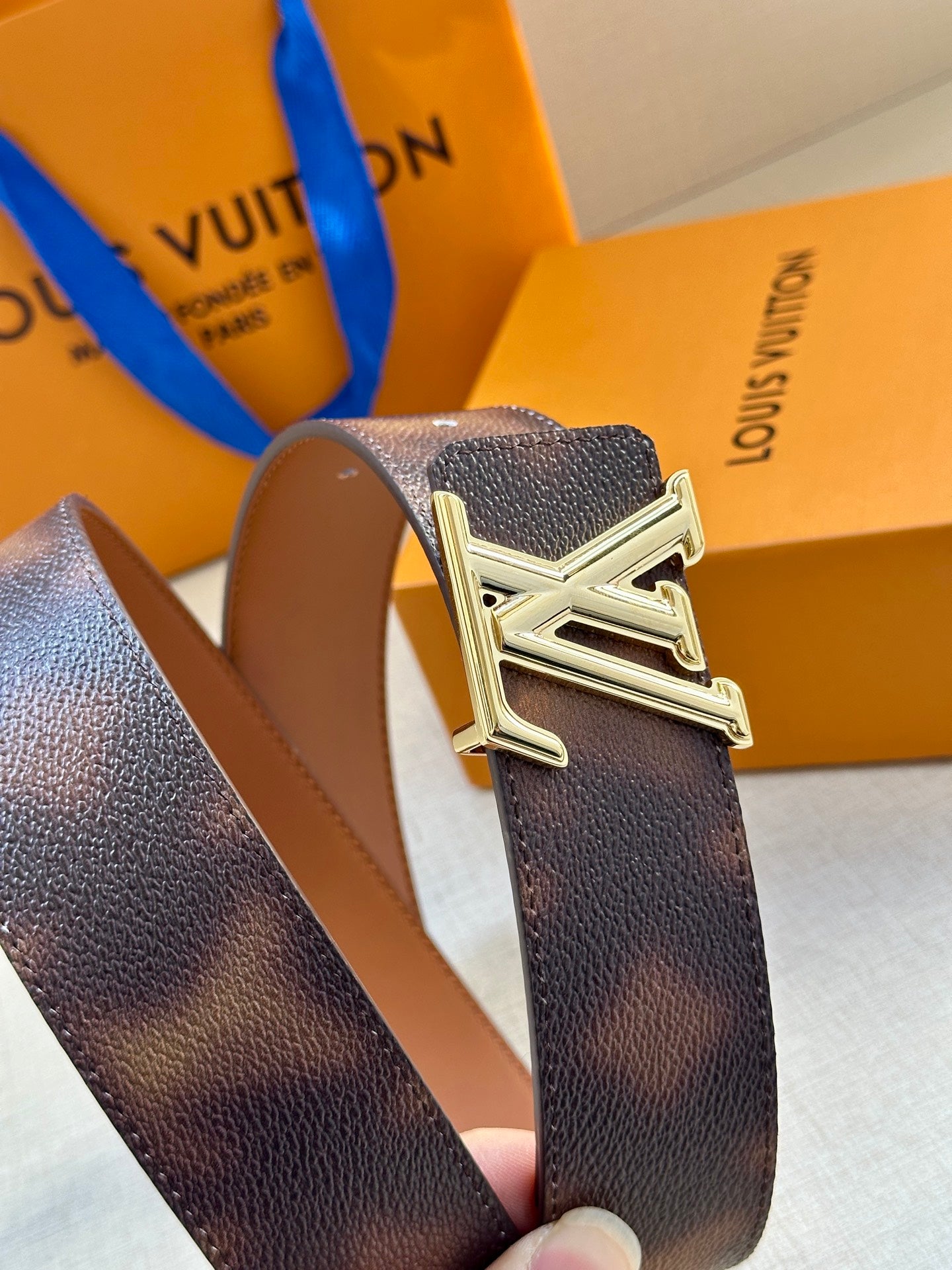 Close-up of dark brown leather belt with silver-tone LV buckle.