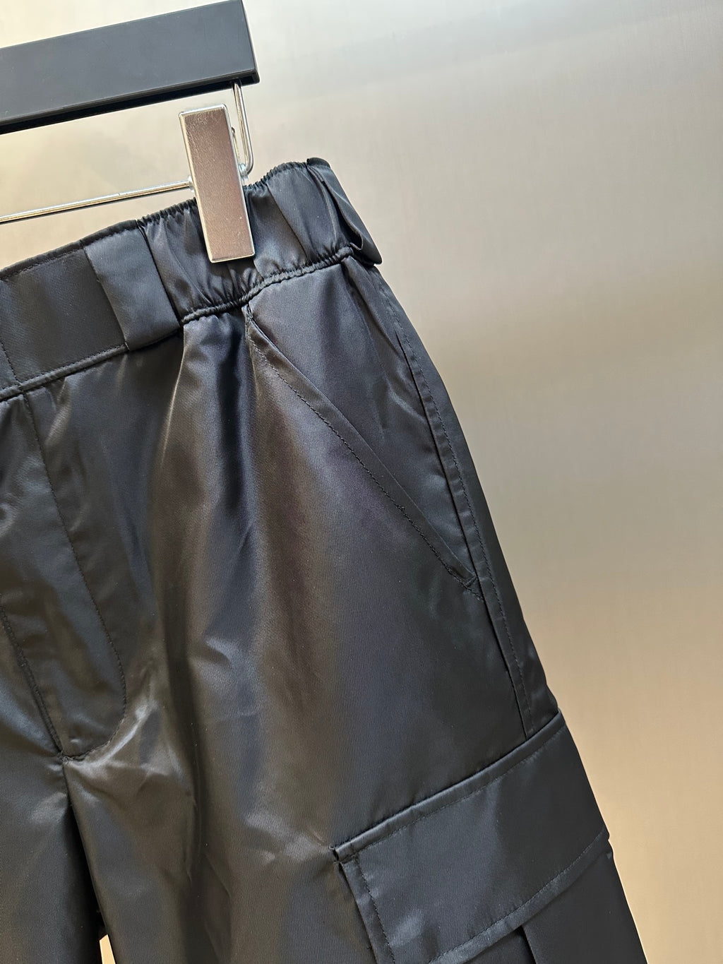 Prada nylon shorts, black, side close-up with stitched cargo pocket and tapered leg hem
