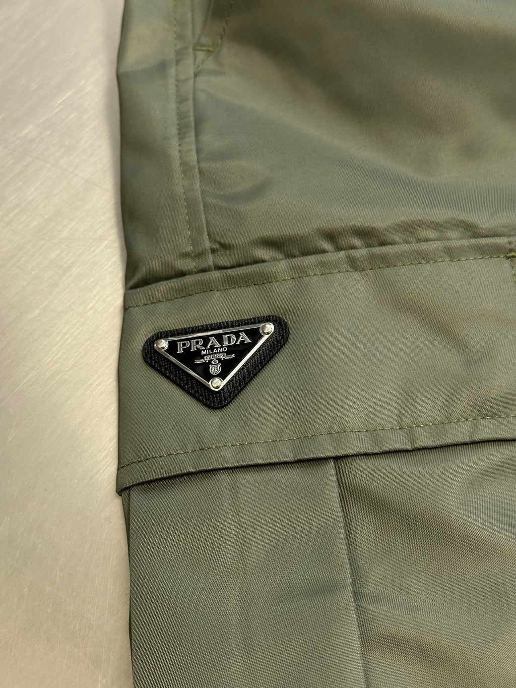 Prada cargo shorts close-up with PRADA logo label on side pocket flap