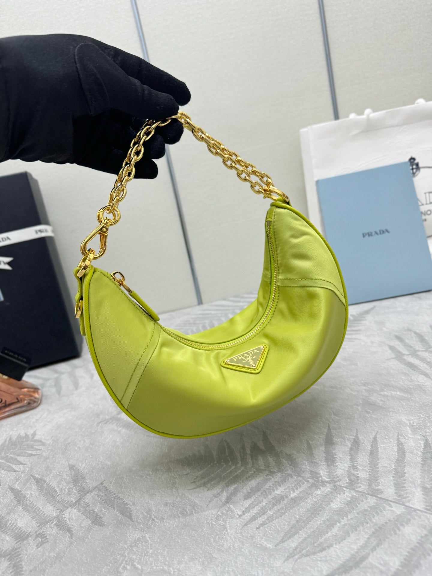 Lime green crescent shoulder bag with gold chain strap and top zip