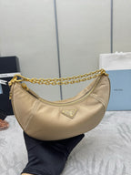 Beige crescent bag with gold chain handle, zip top, and triangular logo