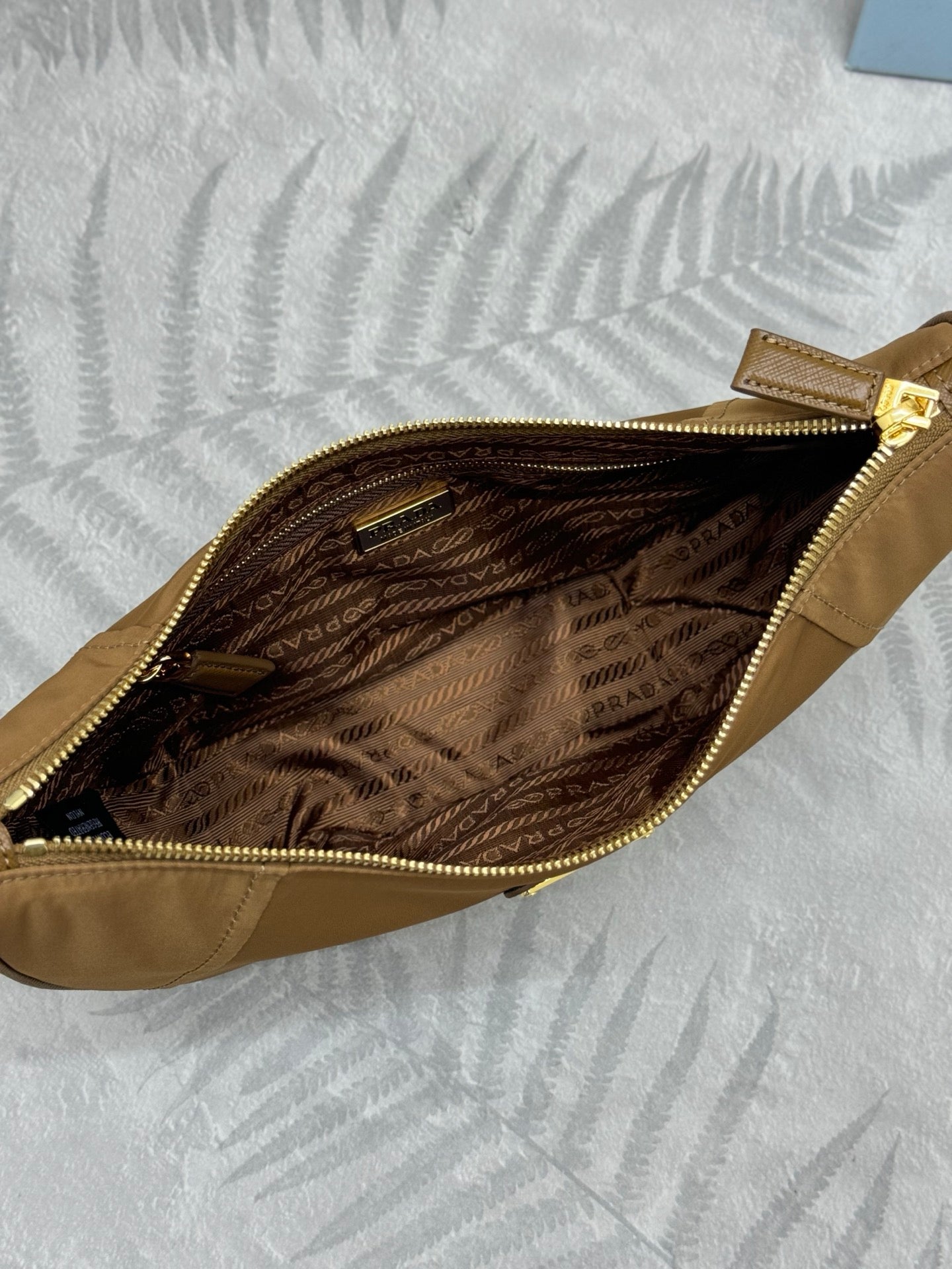 Prada tan hobo bag interior with patterned lining and visible zip closure.