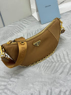 Prada tan leather hobo bag with gold chain, front crest logo, and zip top.