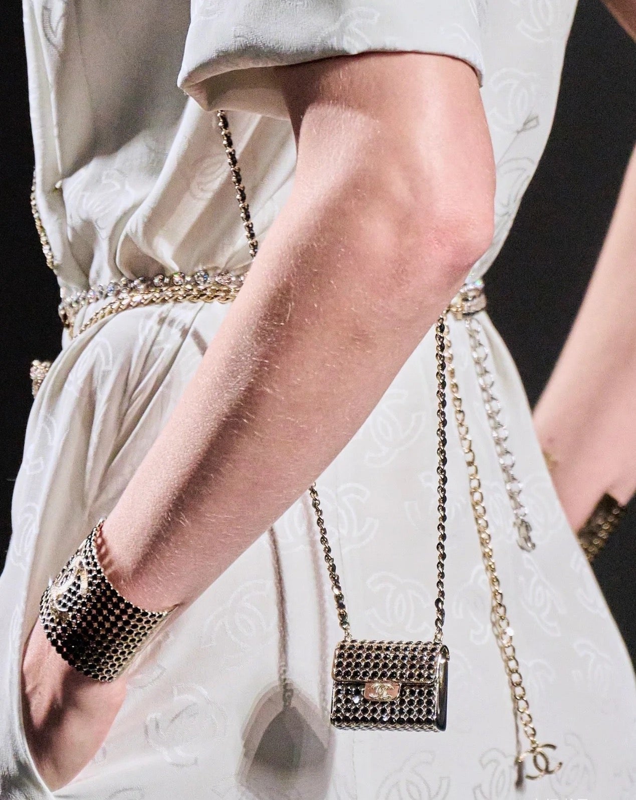 Chanel mini flap crossbody bag with silver ring-mesh front and gold chain on white dress