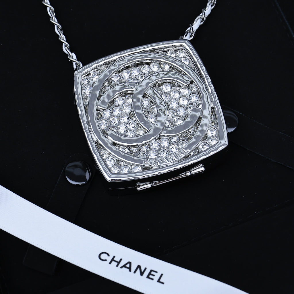 Silver-tone rhinestone square pendant necklace with ornate circular emblem
